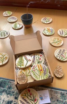 a box filled with cookies sitting on top of a wooden table next to a cup