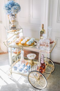 a gold bar cart filled with cupcakes and drinks