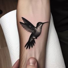 a black and white hummingbird tattoo on the arm