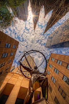 looking up at the statue in front of tall buildings