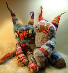 two knitted stuffed animals sitting next to each other on top of a white rug