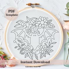 an embroidery pattern with flowers and leaves on the hoop next to a vase full of flowers