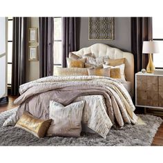 the bed is made up with gold and silver comforters, pillows, and blankets