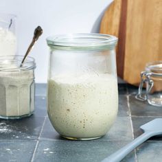 a glass jar filled with food sitting on top of a counter next to two spoons