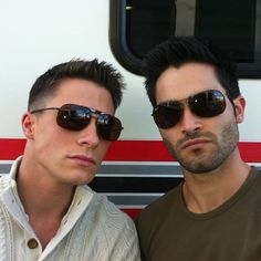 two men in front of a bus wearing sunglasses