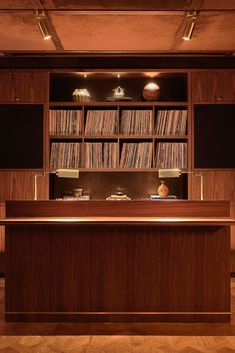 an image of a wooden bar with records on the shelves and lights above it in a room