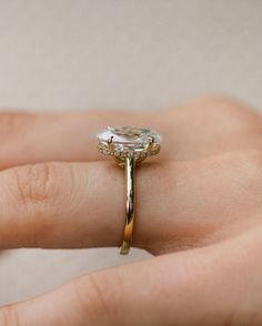 a woman's hand holding a ring with a large diamond on the middle of it