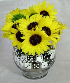 a vase filled with lots of yellow flowers and black and white polka dot dices