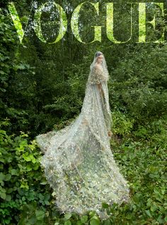 a woman in a wedding dress is standing in the woods with her veil blowing in the wind