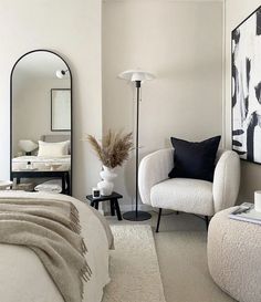 a bedroom with a bed, chair and mirror