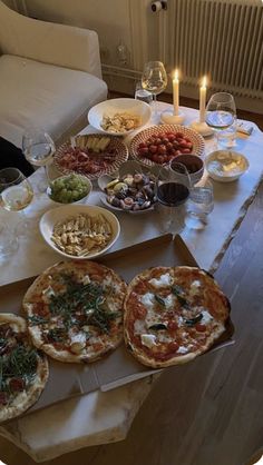 pizzas and appetizers on a table with candles in front of the couch