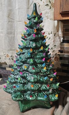 a green ceramic christmas tree sitting on top of a table next to a wooden shelf