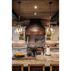 a large kitchen with an island and two pendant lights hanging from it's ceiling