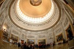 the inside of a building with many people standing in front of it and looking up at the ceiling