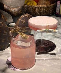 a pink drink in a glass next to a brown bag and some other items on a table