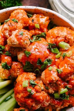 a bowl filled with meatballs and celery on top of a wooden table