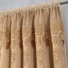 gold embroidered curtains hanging on the side of a window