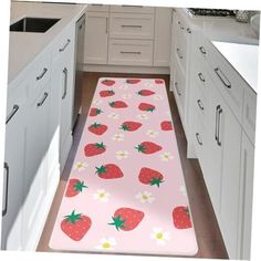 a pink kitchen mat with strawberries and daisies printed on the floor next to white cabinets