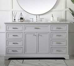 a white bathroom vanity with a round mirror above it and plants on the counter top