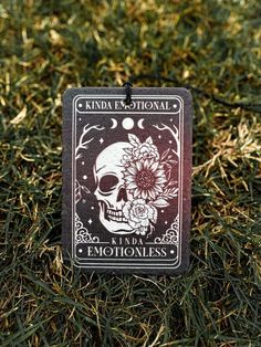 a card with a skull and flower on it sitting in the middle of some grass