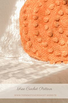 an orange round object sitting on top of a white cloth covered tablecloth with the words free crochet pattern below it