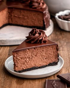 a piece of chocolate cheesecake on a plate with one slice cut out and ready to be eaten