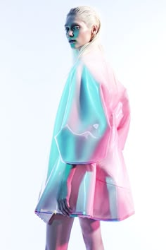 a woman in a pink and blue raincoat is standing on the runway with her hands behind her back