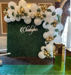 balloons and greenery decorate the backdrop for a christmas party in an elegant room with green carpeting