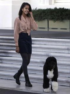 a woman talking on her cell phone while walking with a poodle in front of the white house