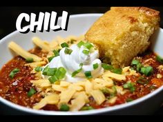 chili with cornbreads and sour cream in a white bowl on top of a table