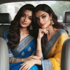 two women sitting in the back seat of a car wearing matching sari and jewelry