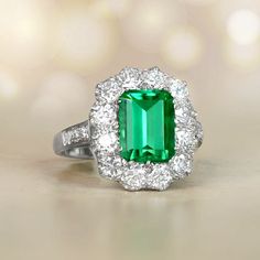 an emerald and diamond ring on a table