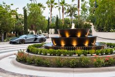 a car is parked in front of a fountain with lights on it's sides