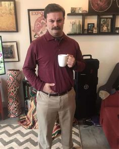 a man standing in a living room holding a coffee cup