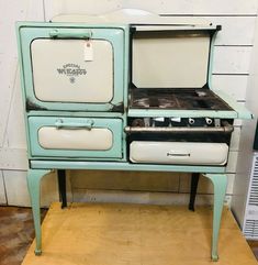 an old fashioned stove sitting on top of a wooden table next to a white wall