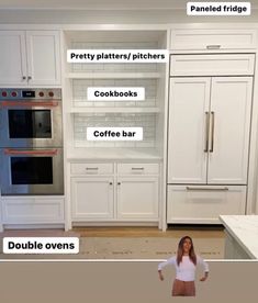 a woman is standing in the middle of a kitchen with white cabinets and appliances on display