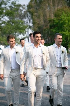 men in white suits are walking down the street