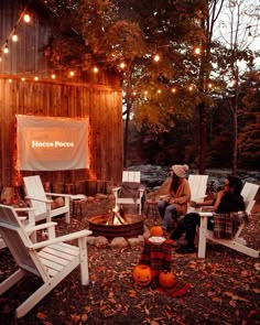 people sitting around a fire pit with lights strung from the roof and on the ground