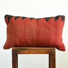 a red and black pillow sitting on top of a wooden chair