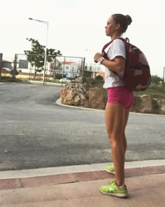 a woman in pink shorts is standing on the sidewalk with her back to the camera