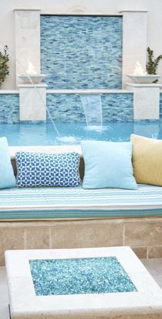 a couch sitting next to a swimming pool filled with blue and yellow pillows on top of it