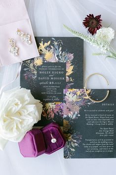 the wedding stationery is laid out on top of the bride's dress and bouquet