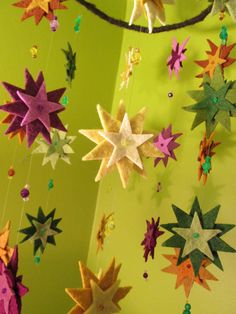 a mobile with stars hanging from it's sides on a green wall in a room