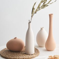 three vases and one bowl are on a table with food in front of them