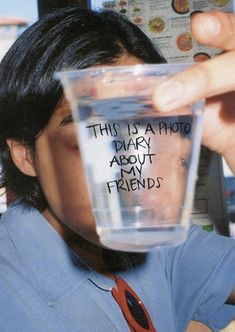 a man holding up a glass with writing on the side and his face in it