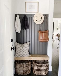 a bench with baskets and hats on it in front of a wall mounted coat rack