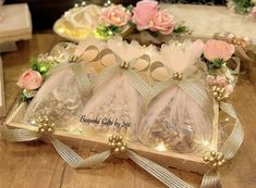 three bags filled with nuts sitting on top of a wooden table next to pink roses