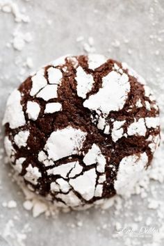 a chocolate crinkle cookie is covered in powdered sugar on a white surface