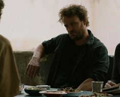 two men sitting at a table with plates of food