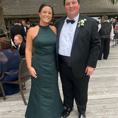 a man and woman standing next to each other on a wooden deck in formal wear